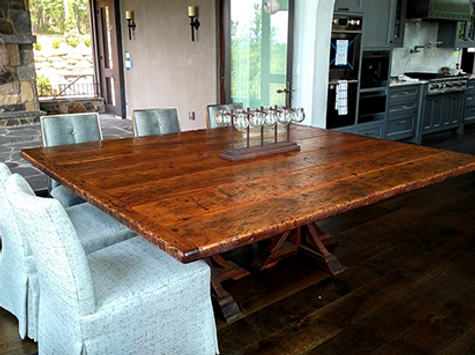 Square wooden dining table with upholstered chairs in a modern kitchen setting