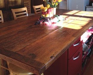 Wooden kitchen island with a red base, topped with fruit and flowers