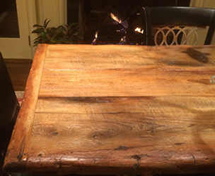 Wooden dining table in front of a fireplace, with a chair visible
