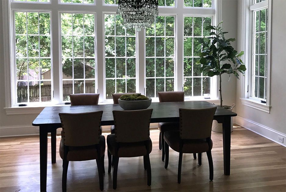 Dining room with dark wood table, chairs, large windows, and a chandelier