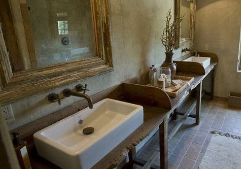 Rustic bathroom with two white sinks on wooden tables, large mirrors, and neutral-toned walls and floor