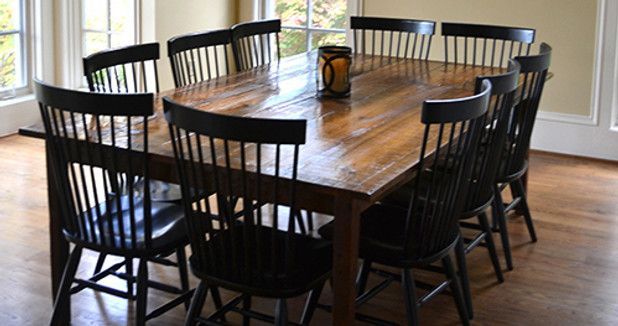 Wooden dining table with black chairs in a room with a window