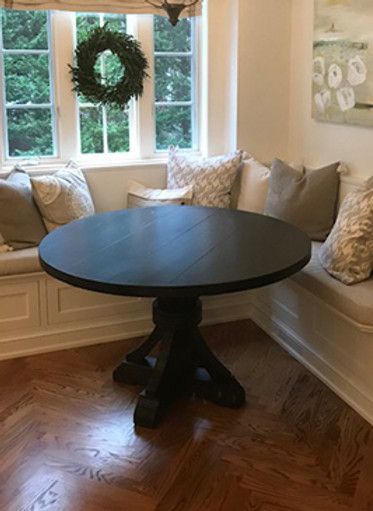 Round black table in a breakfast nook with built-in bench seating and a window