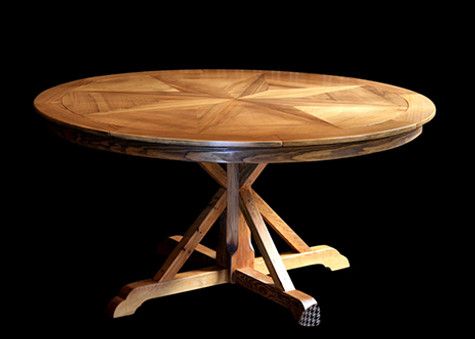 Wooden round table with starburst pattern top and crossed leg base, against black background