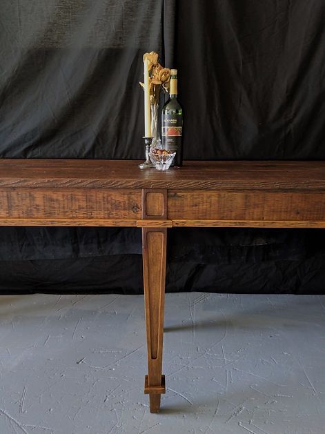 Wooden table with candles and wine bottles against a black backdrop