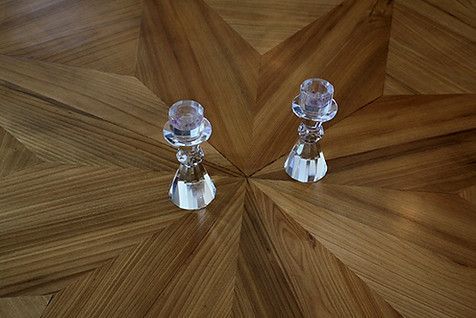 Two crystal candle holders on a patterned wood floor