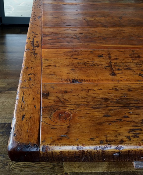 Close-up of a rustic wooden table with a distressed finish, showing knots and imperfections