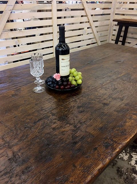 Wooden table set with wine bottle, grapes, crystal glass, and decorative pink flower