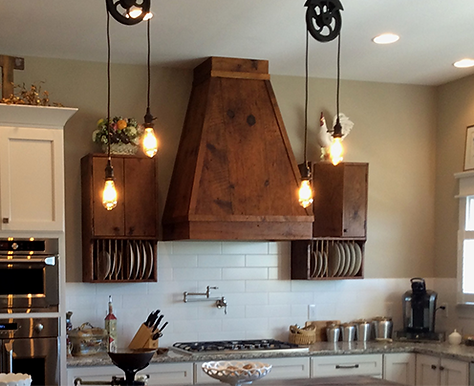 Kitchen with wooden range hood, pendant lights, and plate racks