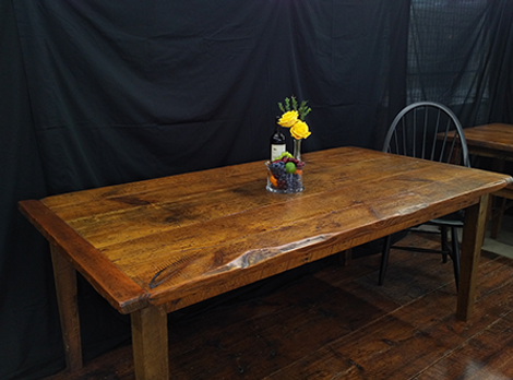 Wooden table with floral centerpiece and chair, set against a black backdrop