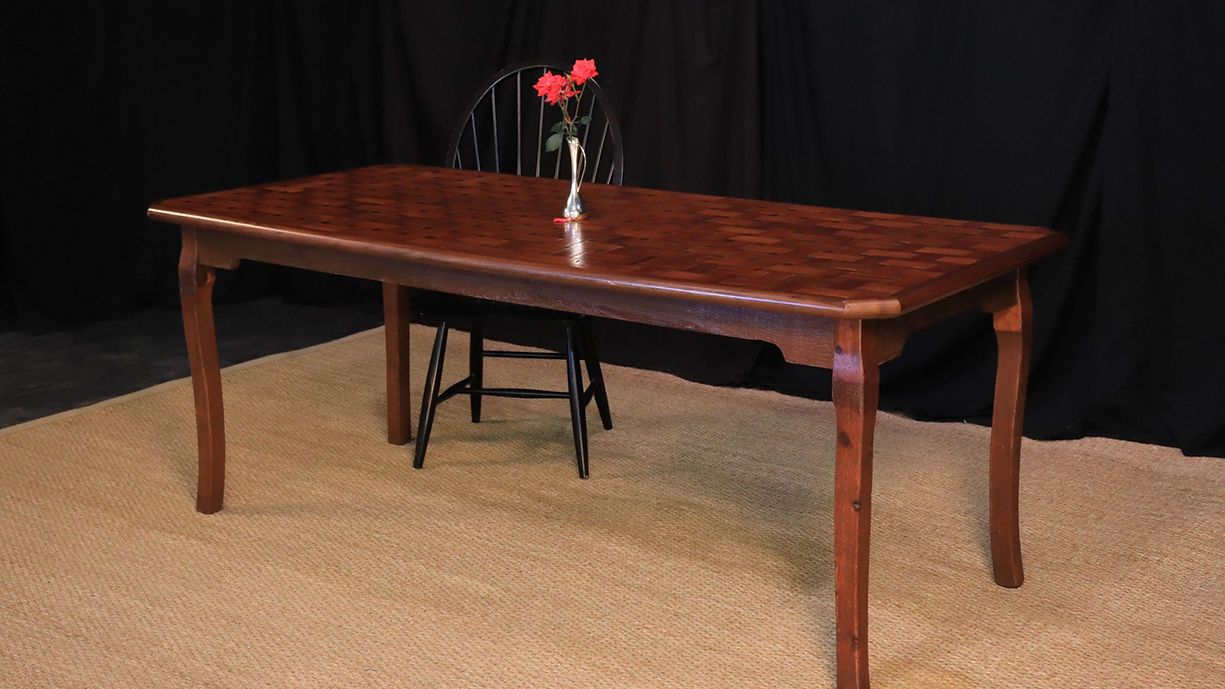 Wooden dining table with flowers, black chair in front of a black backdrop on a beige carpet