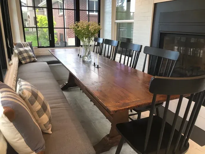 Rustic dining table with black chairs, a bench, and a fireplace