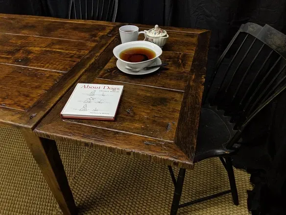 Dark wooden table with tea set, book, and black chair