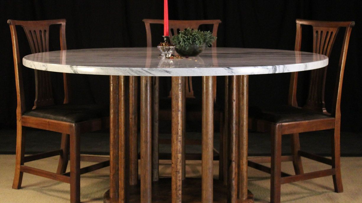 Round dining table with marble top, surrounded by three wooden chairs