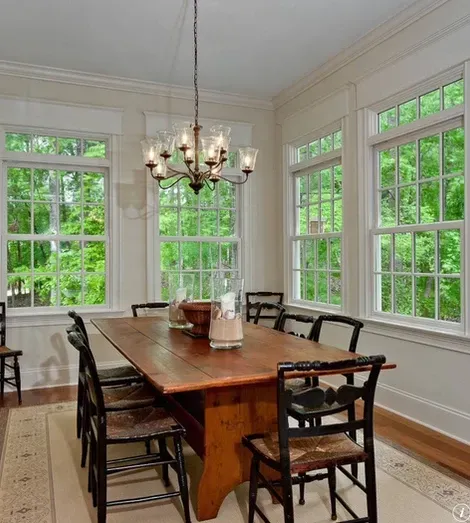 Dining room with wooden table and chairs, large windows with green views, chandelier