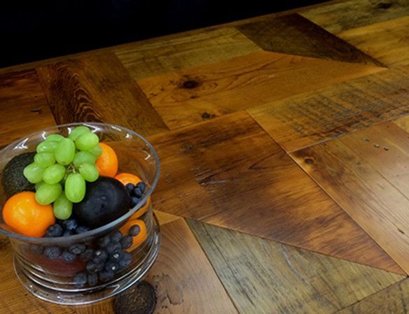 A glass bowl of fruit (grapes, oranges, blueberries, avocado) on a rustic wooden surface