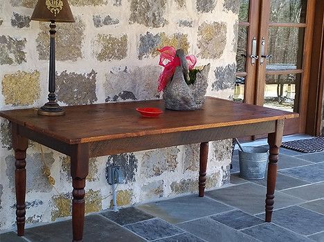 Brown wooden table with decor against a stone wall, lamp and door to the right
