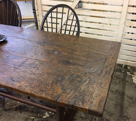 A rustic wooden dining table with two chairs in front of a white slatted wall