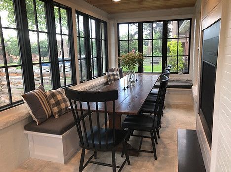 Dining room with long wooden table, seating, and large windows
