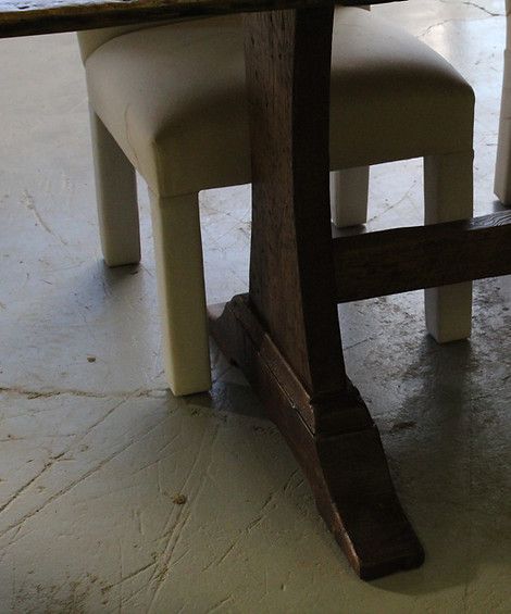Close-up of dark wooden table leg and cream-colored chair