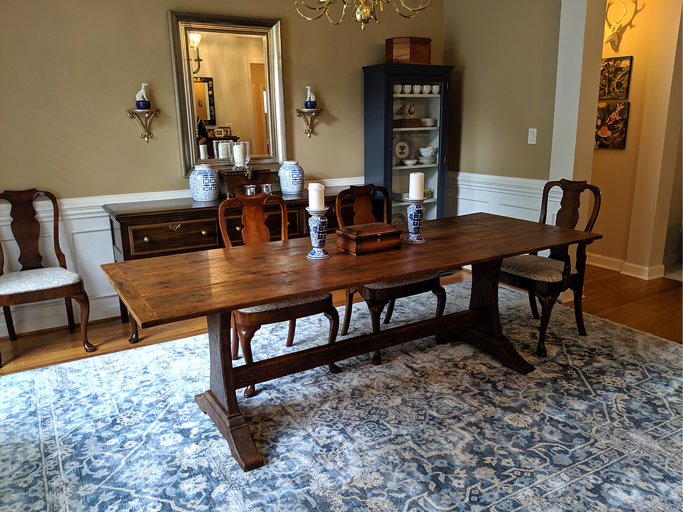 Dining room with wooden table, chairs, blue rug, and decorative items on walls and furniture