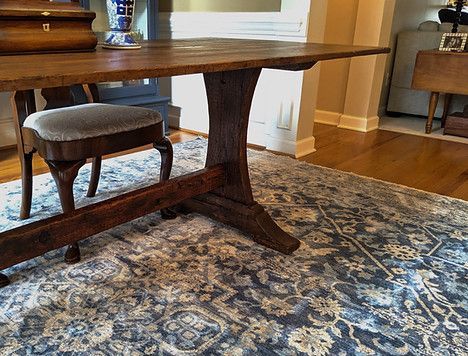 Wooden table with intricate base, chair, and blue patterned rug