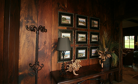 Wooden wall with framed landscape paintings and a decorative console table