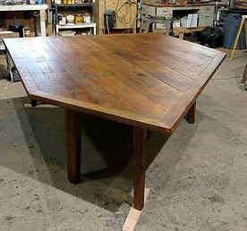 Triangular wooden table with visible wood grain, in a workshop setting
