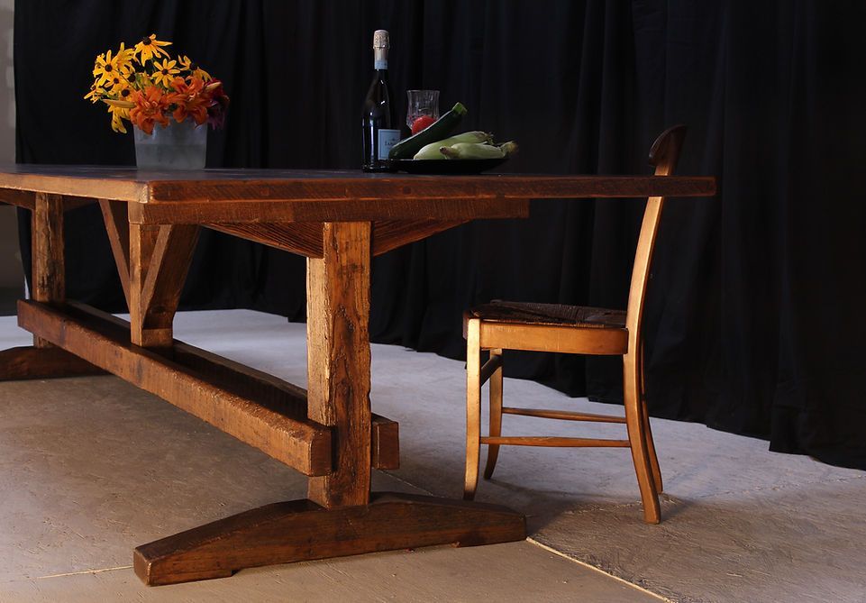 Wooden dining table set with flowers, wine, and a chair