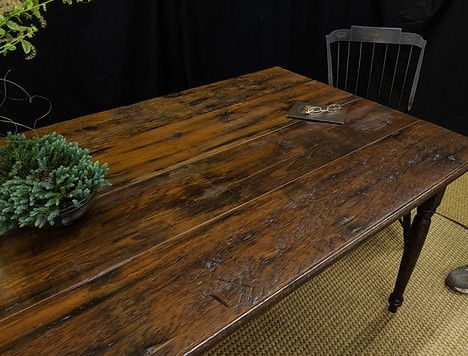 Wooden table with a green plant, a chair, and a dark backdrop