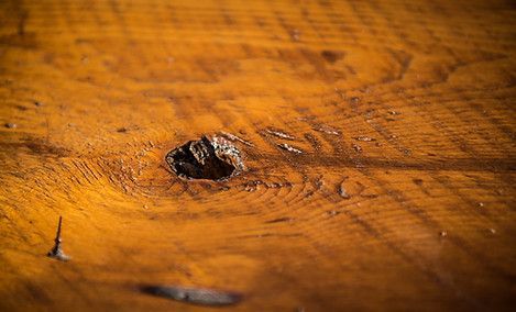 Close-up of weathered, stained wood with a knot hole and visible grain