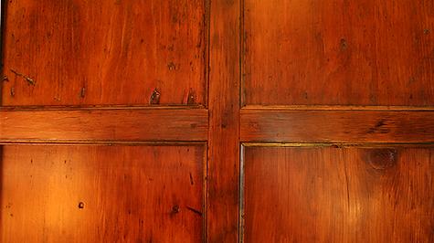 Close-up of a wooden door with a cross-shaped design, showing variations in brown tones and textures