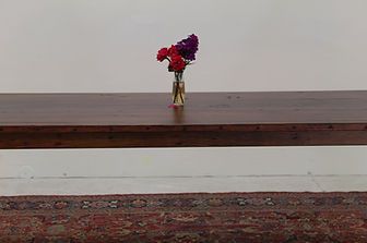 Dark wooden table with vase of red and purple flowers on a rug