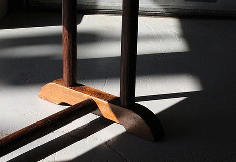 Brown wooden table base with shadows on a white floor