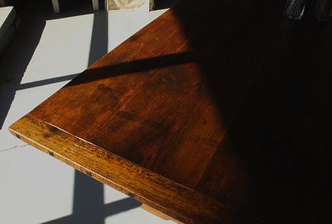 Wooden table corner, partially shadowed by sunlight