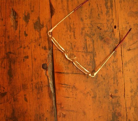 Eyeglasses on an aged, orange-brown wooden surface, slightly angled