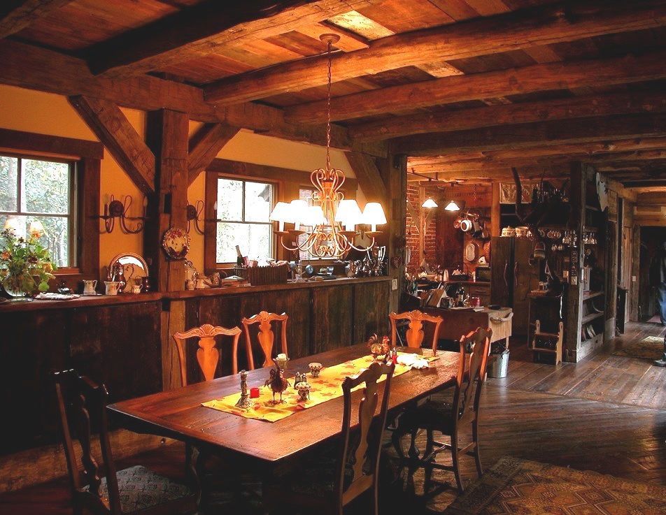 Rustic dining room with wooden beams, table set for meal, chandelier, and open kitchen