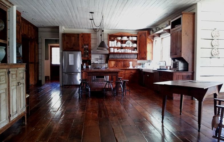 Rustic kitchen with wood floors, cabinets, and island. Stainless steel refrigerator