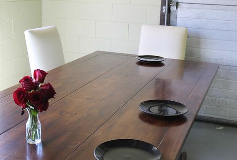 Wooden table with black plates and two white chairs