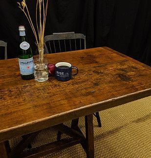 Wooden table with water bottle, mug, vase of branches, and chair