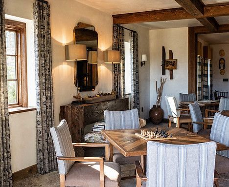 A cozy interior with wooden tables, chairs, and curtains, warm lighting, and a mirror