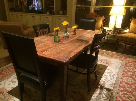 Dining room with wooden table, black chairs, flowers, and rug