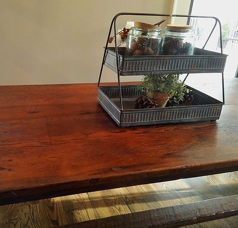 Rustic wooden table with a two-tiered metal tray holding jars and a small potted plant