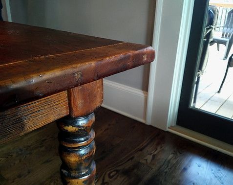 Wooden table with turned leg, dark wood floor, near sliding glass door