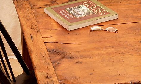 Wooden desk with book, glasses, and a chair