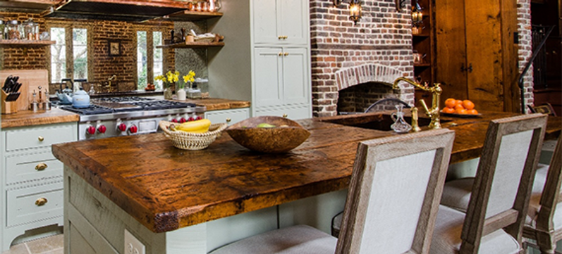 Rustic kitchen with wood cabinets, brick wall, island, and stainless steel appliances