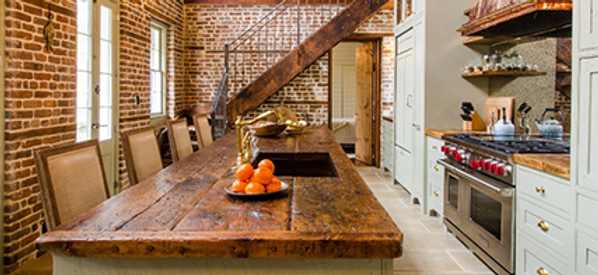 Open-plan kitchen with brick walls, wooden ceiling, a loft, and a bar-style island with three chairs