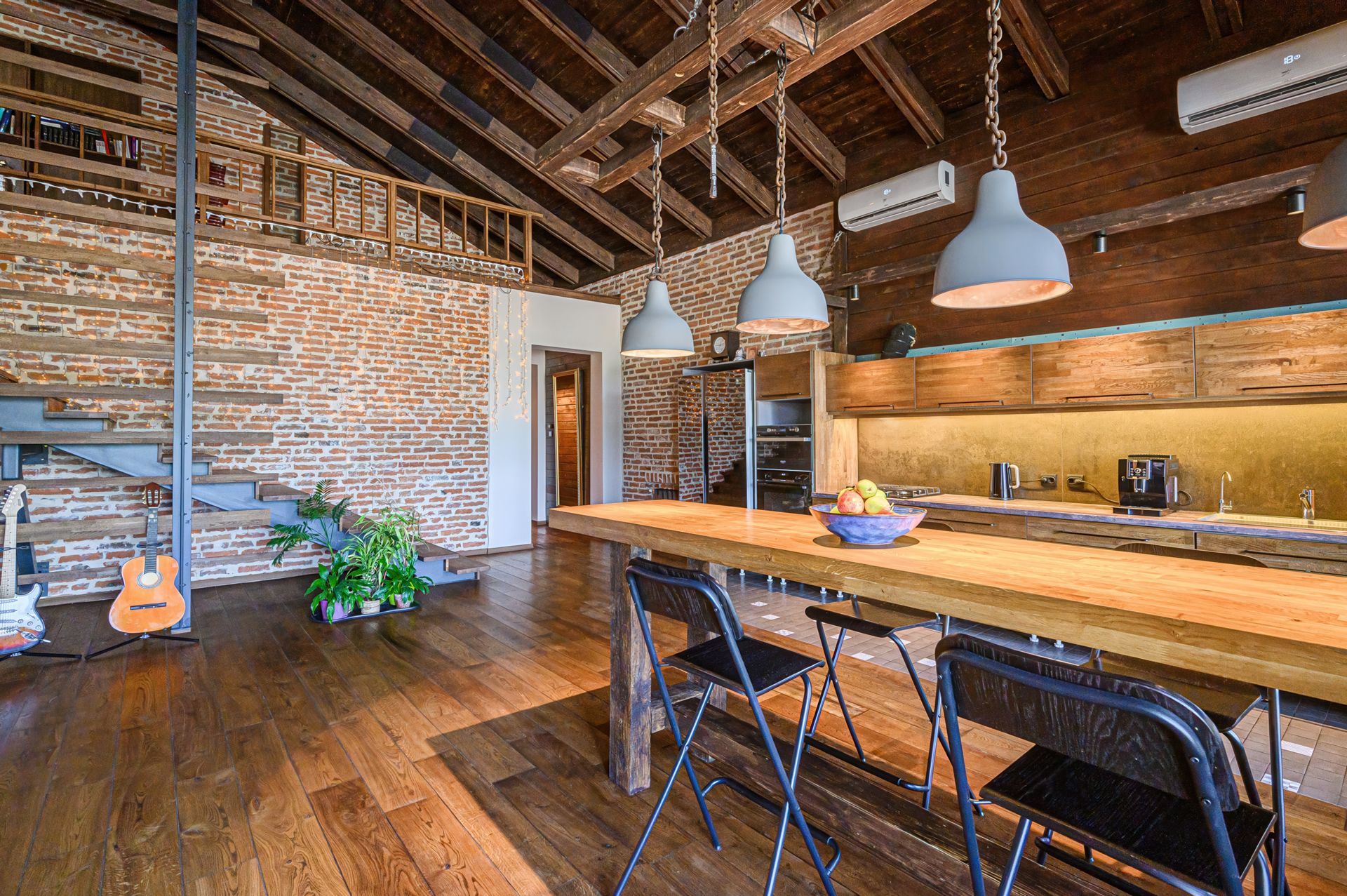 Open-plan kitchen with brick walls, wooden ceiling, a loft, and a bar-style island with three chairs