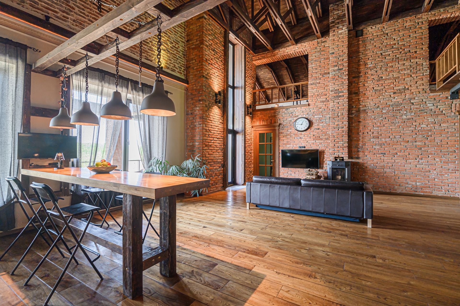 Loft interior with exposed brick walls, wooden floors, and a kitchen island, bathed in sunlight