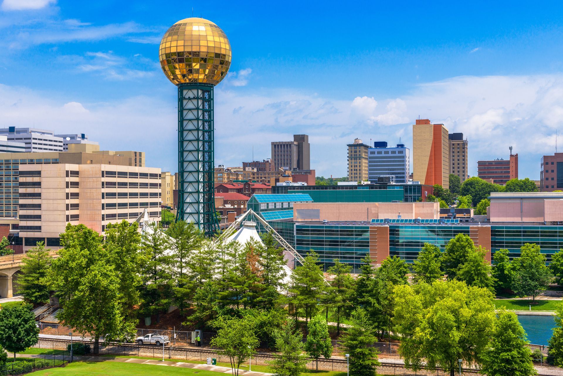 Knoxville, TN skyline with the golden Sunsphere tower, trees, and buildings against a blue sky